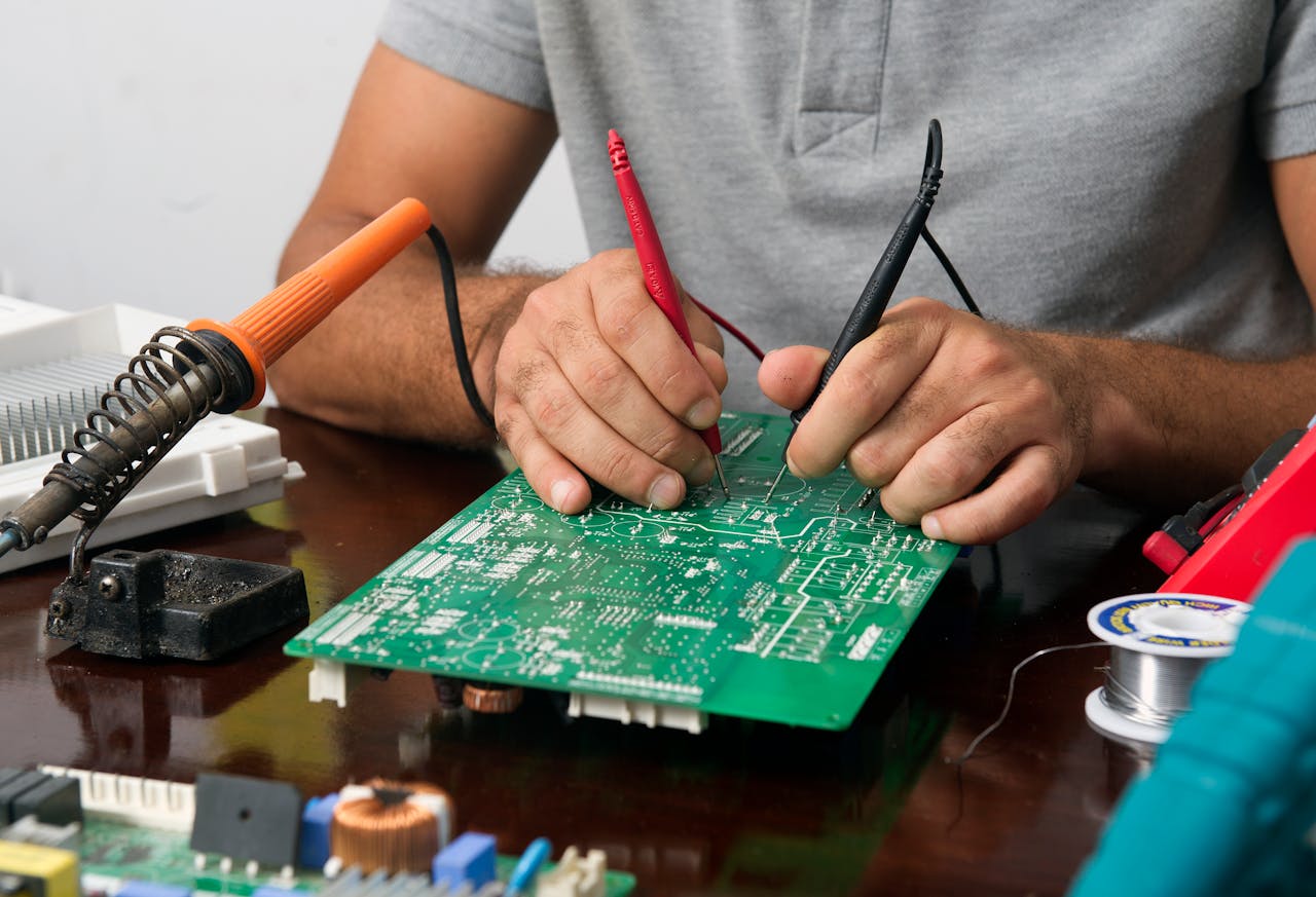 Services Close-up of a technician repairing an electronic circuit board with precision tools.