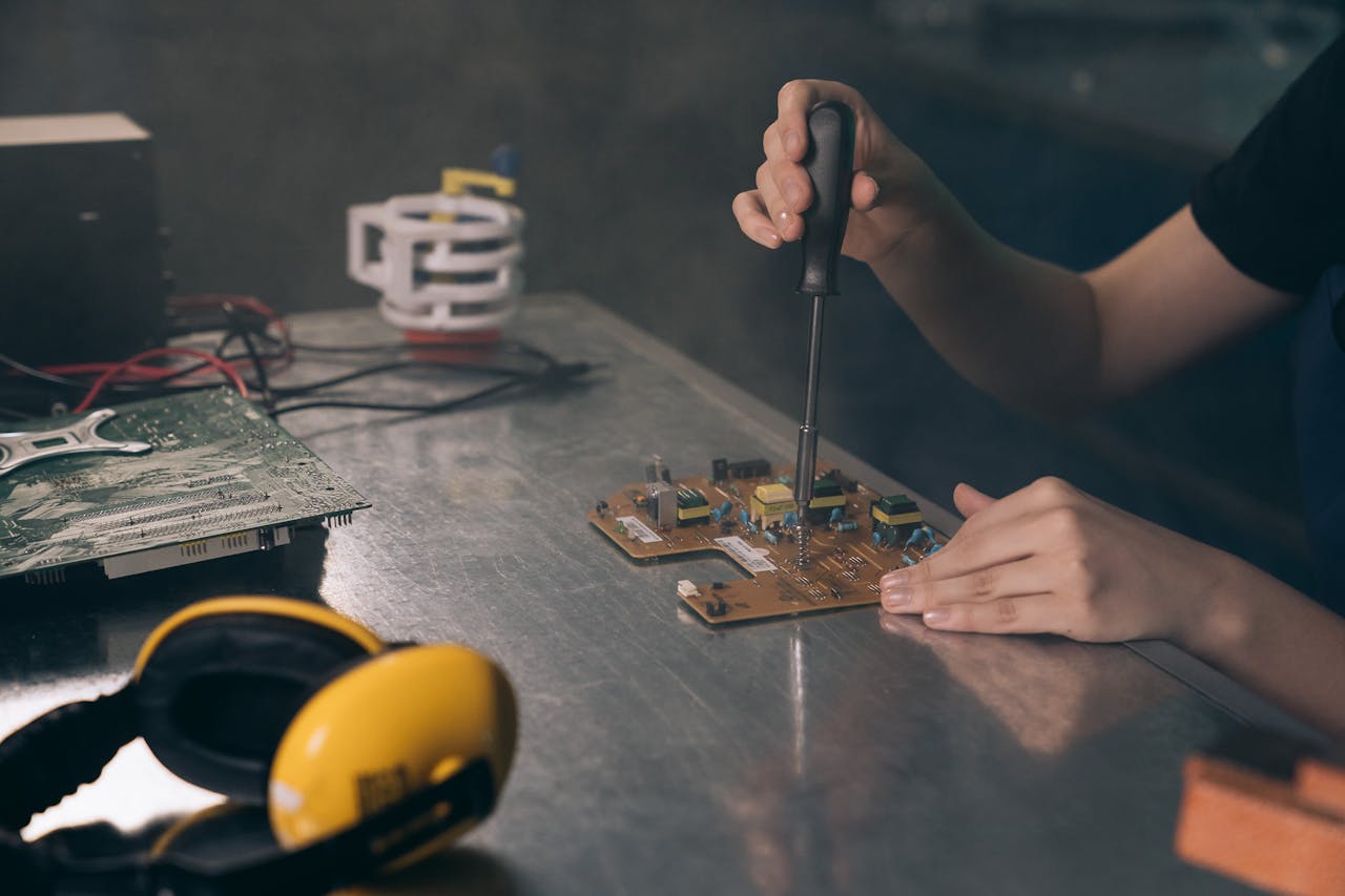 Services Close-up of hands working on electronic circuit board in workshop.